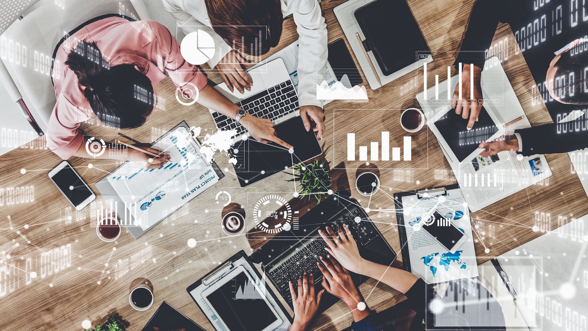 team of people working together around a table with overlaying white data graphics