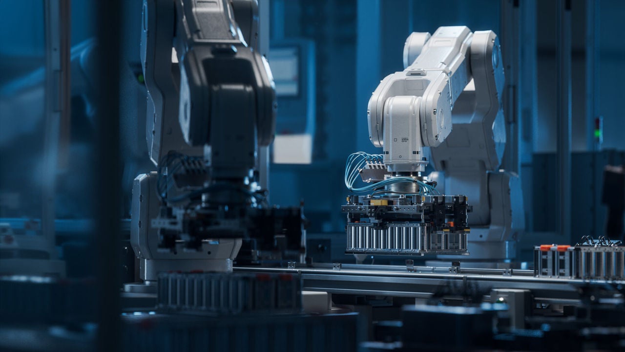 Modern EV Factory. On Automated Production Line Robot Arms Transporting Automotive Battery Modules onto Conveyor Belt. Electric Car Battery Pack Manufacturing Process.