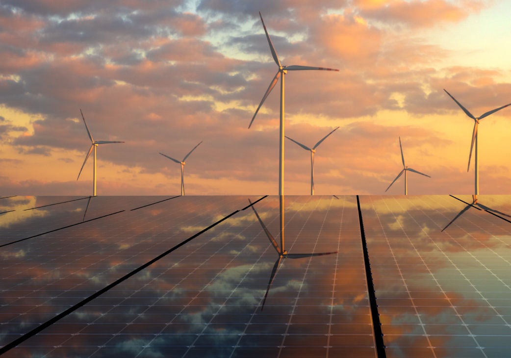 windmills and solar panels in front of a sunset sky
